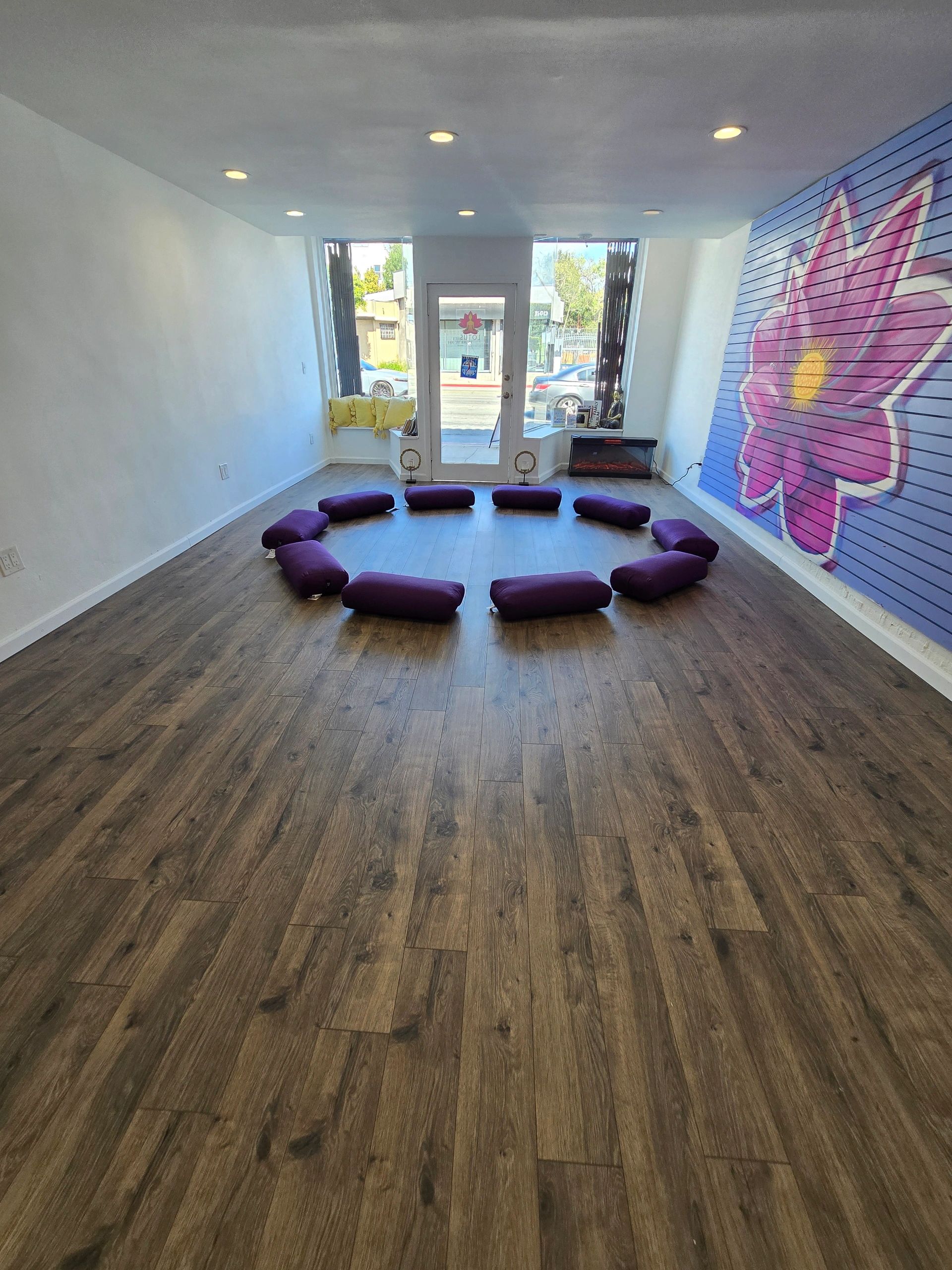 Purple yoga bolsters and a colorful lotus mural in the studio